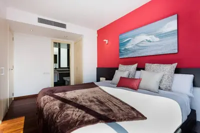 a bedroom with a red wall and a large bed at Modern Luxury Apartment Fira Bcn in Hospitalet de Llobregat