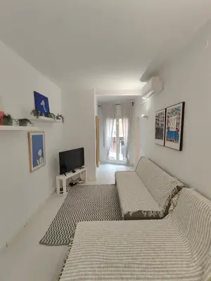 a white room with a bed and a tv at Family apartment close to Parc Güell in Barcelona