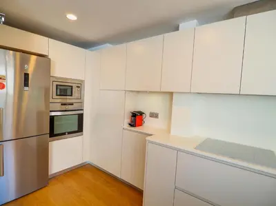 a kitchen with white cabinets and a stainless steel refrigerator at Elite Bonaire Penthouse by Hello Homes Sitges in Sitges