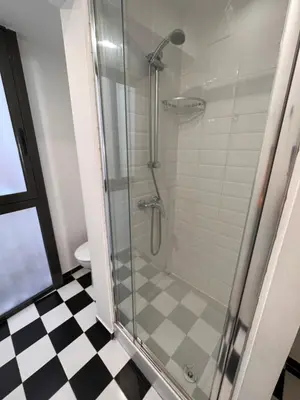 a glass shower in a bathroom with a checkered floor at Sagrada Familia- Excelente Ubicación in Barcelona