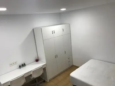 a white room with a bed and a white cabinet at Piso céntrico con Parking a 20min de Barcelona in Terrassa