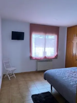 a bedroom with a bed and a window and a chair at Piso céntrico con Parking a 20min de Barcelona in Terrassa