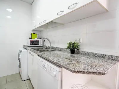 a white kitchen with a sink and a microwave at Golden Sands by Hello Homes Sitges in Sitges