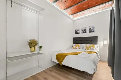 a white bedroom with a bed and a window at Tendency Apartments 5 in Barcelona