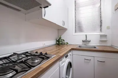 a white kitchen with a stove and a sink at CENTRIC APARTMENT GAUDI in Barcelona