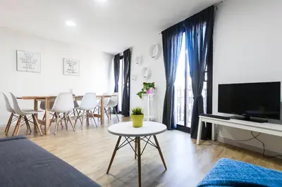 a living room with a couch and a tv and a table at Be Barcelona Plaza Catalunya in Barcelona