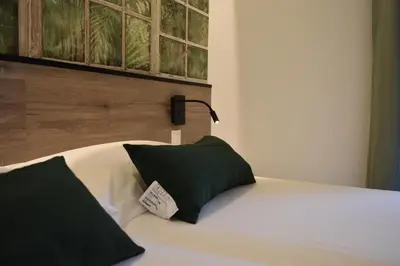a bed with a green pillow and a lamp on it at Casp Green House in Barcelona