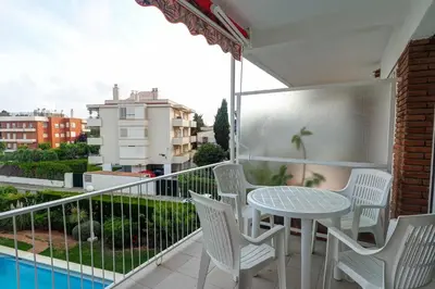 a balcony with a table and chairs and a pool at Sitges with pool near beach by Hello Homes Sitges in Sitges