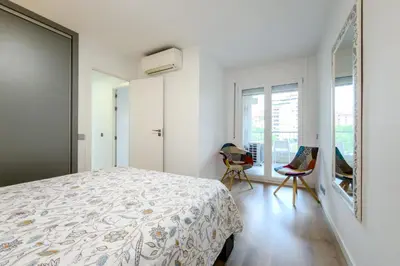 a white bedroom with a bed and two chairs at Impresionante Apartamento delante del Mar in Vilassar de Mar