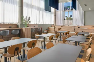 a dining room with tables and chairs and windows at B&B HOTEL Barcelona Viladecans in Viladecáns