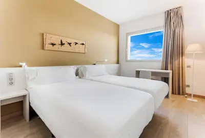a hotel room with two beds and a window at B&B HOTEL Barcelona Viladecans in Viladecáns