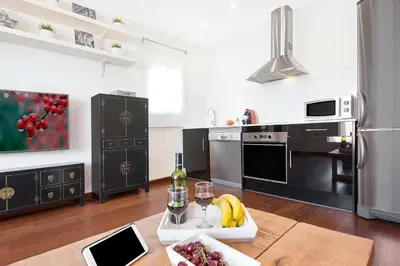 a kitchen with a table with a glass of wine and fruit at Atic Barcelona in Barcelona