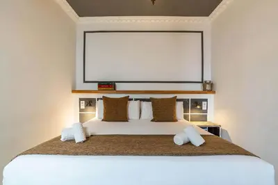 a bedroom with a large white bed with a large screen at Casa Gracia Apartments in Barcelona