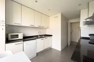 a white kitchen with a sink and a microwave at chicStays Apartment Ciutadella Park in Barcelona