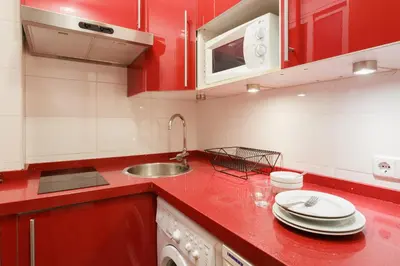 a red kitchen with a sink and red cabinets at ApartEasy - Turo Park with lovely balcony in Barcelona