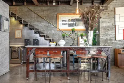 a kitchen with a bar with stools and a staircase at THE LOFT - with private pool & jacuzzi in Corbera de Llobregat