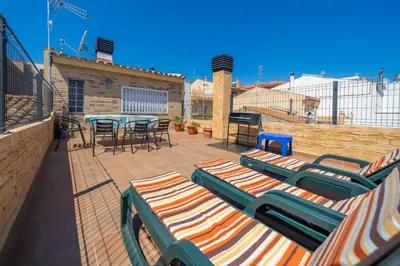 a patio with chaise lounges and a table and chairs at HomeHolidaysRentals Benoit - Costa Barcelona in Pineda de Mar