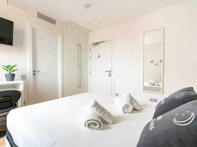 a white bedroom with a large white bed and a window at Limehome Barcelona Carrer de Fontcoberta - Digital Access in Barcelona
