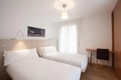 a hotel room with two beds and a desk at Casa Codina in Barcelona