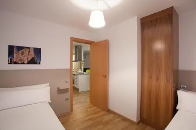 a bedroom with two beds and a wooden door at Casa Codina in Barcelona