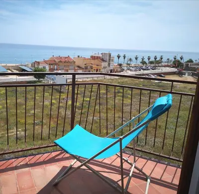 a blue chair sitting on a balcony overlooking the ocean at ÁTICO FRENTE AL MAR in Canet de Mar