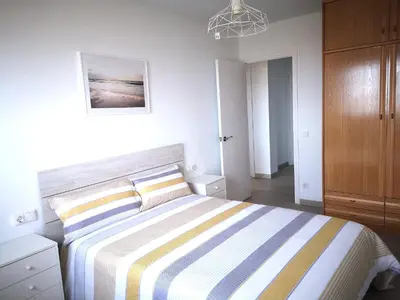 a bedroom with a large bed with a striped blanket at ÁTICO FRENTE AL MAR in Canet de Mar