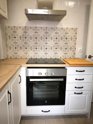 a kitchen with white cabinets and a stove top oven at ÁTICO FRENTE AL MAR in Canet de Mar