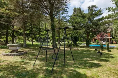 a swing set in a park with a pool at L'aviador de Can Ton in Sant Llorenc Savall