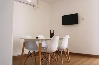 a table with white chairs and a television on a wall at MonResidence Bellavista in Manresa