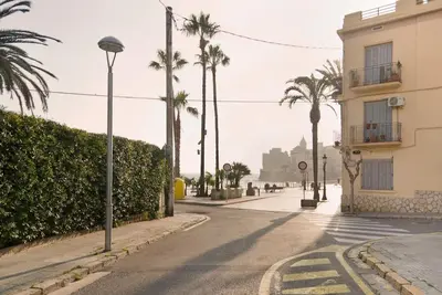 an empty street with palm trees and a building at Sitges in centrum close to the beach in Sitges