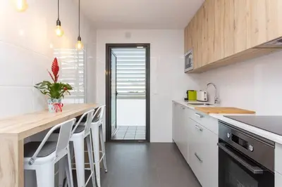 a kitchen with white cabinets and a counter with stools at New Apartment With Private Rooftop in Hospitalet de Llobregat