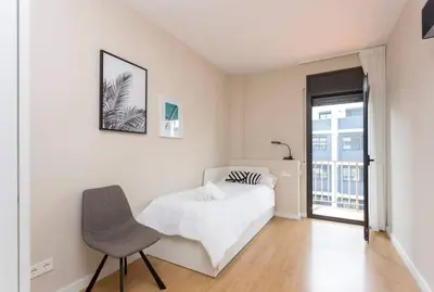 a bedroom with a bed and a chair and a window at New Apartment With Private Rooftop in Hospitalet de Llobregat