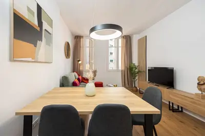a dining room with a table and chairs and a television at Charming 2br In Trendy Gracia in Barcelona