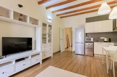 a large kitchen with white cabinets and a flat screen tv at Housalia Gracia in Barcelona