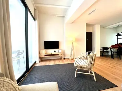 a living room with a chair and a television at Hauzify I Apartaments Sant Pau in San Pol de Mar