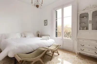 a white bedroom with a large bed and a window at Sagrada Familia 4 Bedrooms 