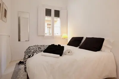 a bedroom with a large white bed with black pillows at Sagrada Familia 4 Bedrooms 