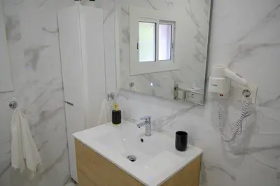 a white bathroom with a sink and a hair dryer at Relax House Barcelone in Sant Esteve Sesrovires
