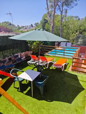 a table and chairs with an umbrella on the grass at Relax House Barcelone in Sant Esteve Sesrovires