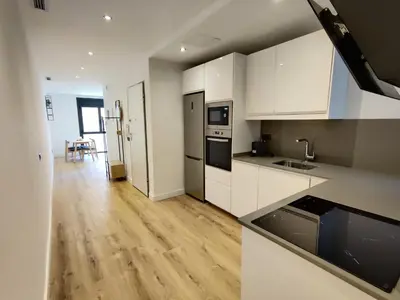 a kitchen with white cabinets and a wooden floor at Stylish apartments Camp Nou in Hospitalet de Llobregat
