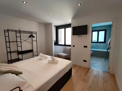 a bedroom with a large bed and a living room at Stylish apartments Camp Nou in Hospitalet de Llobregat