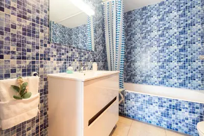 a blue tiled bathroom with a sink and a tub at Apartamento con gran patio y excelente ubicación! in Mataró