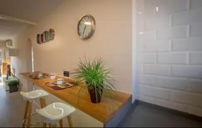 a table with a potted plant and a clock on a wall at Beachfront Sunny Apartment , Sea & Mountain View in Castelldefels