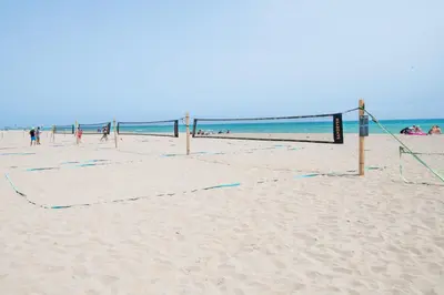 a volley ball net on a beach with people playing at Beachfront Sunny Apartment , Sea & Mountain View in Castelldefels