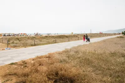 a couple walking down a road next to the beach at Beachfront Sunny Apartment , Sea & Mountain View in Castelldefels