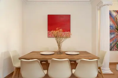 a dining room with a wooden table and white chairs at SibsBcn-Paseo de Gracia Luxury Exclusive Gaudí in Barcelona