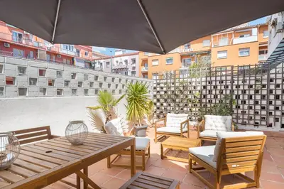 a patio with a table and chairs and an umbrella at Apartment with terrace a step away from Montjuic, Barcelona in Barcelona