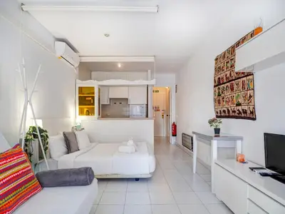 a living room with a white bed and a tv at Ferdinand Apartment by Hello Homes Sitges in Sitges