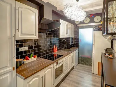 a kitchen with white cabinets and a black tile wall at Flamingo Apartment by Hello Homes Sitges in Sitges