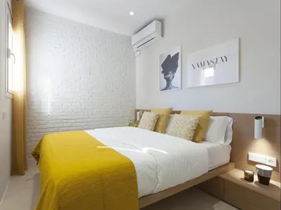 a bedroom with a large bed with a yellow blanket at Sunny Playa Apartment in Barcelona